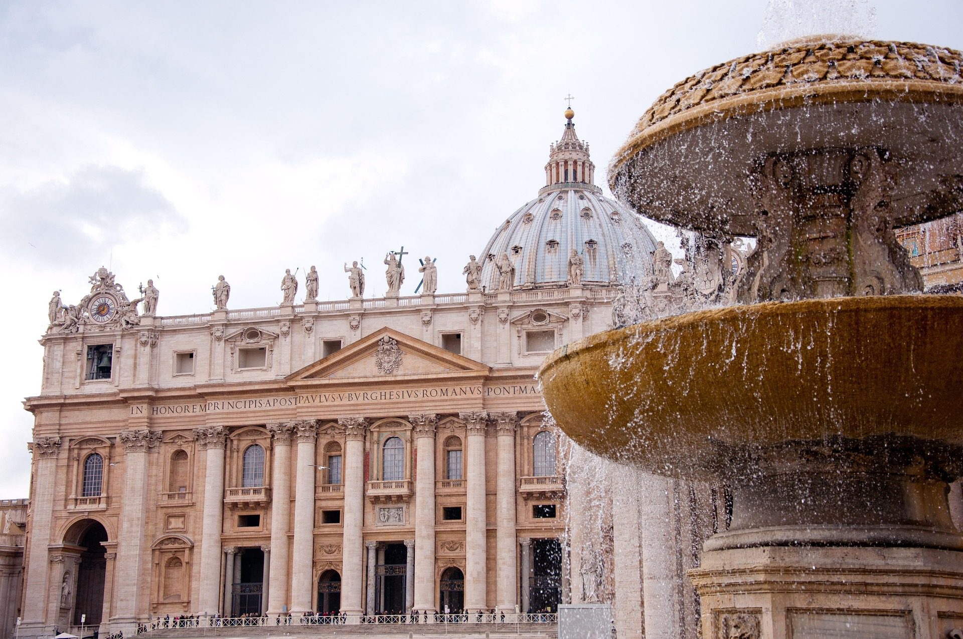 Basílica de São Pedro no Vaticano com cúpula de Michelangelo e fonte jorrando água na Praça de São Pedro, Roma