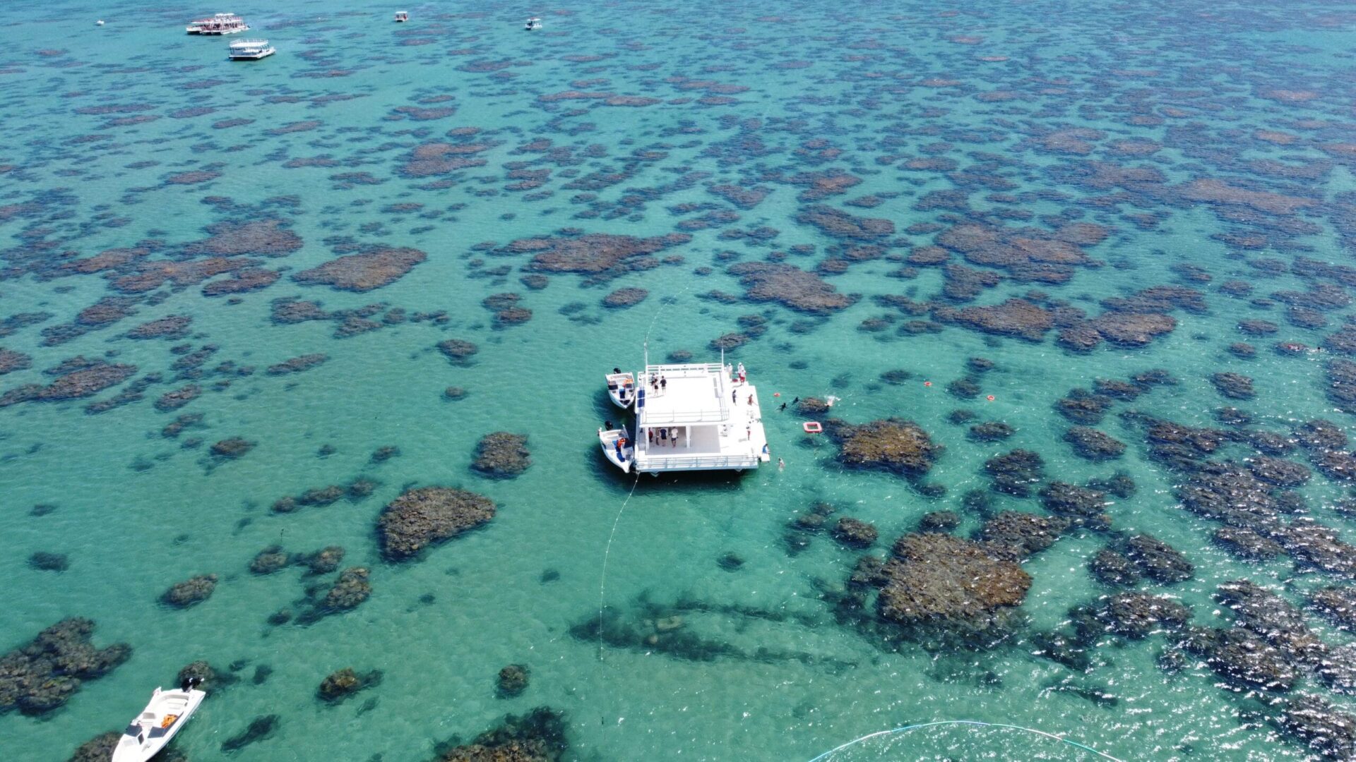 Parrachos de Maracajau em Natal RN - Vista aérea de barco turístico em águas cristalinas com recifes de coral visíveis