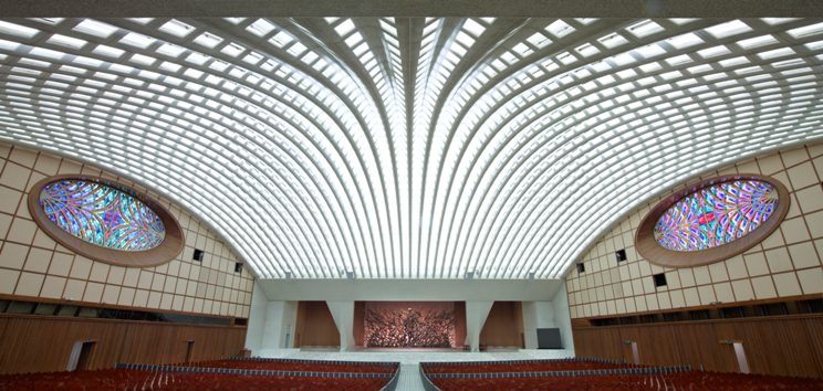 Sala Nervi no Vaticano com teto abobadado em padrão radiante, vitrais circulares coloridos e altar, projetada por Pier Luigi Nervi