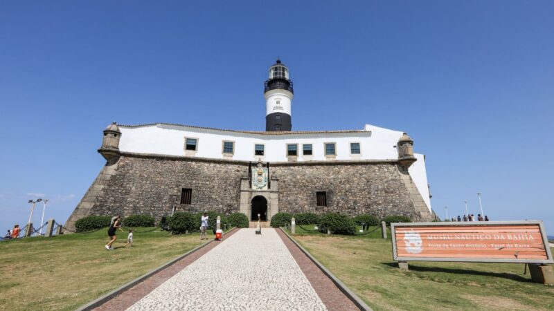 Forte de Santo Antônio da Barra em Salvador Bahia com farol preto e branco, muralhas de pedra, Museu Náutico da Bahia e calçada portuguesa sob céu azul
