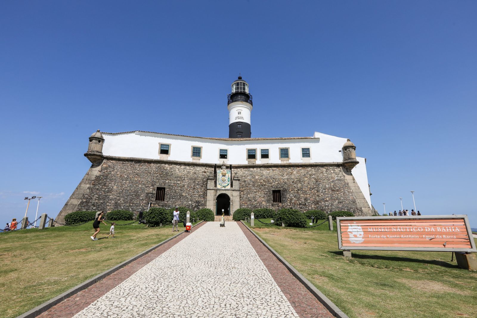Forte de Santo Antônio da Barra em Salvador Bahia com farol preto e branco, muralhas de pedra, Museu Náutico da Bahia e calçada portuguesa sob céu azul