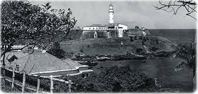 Fotografia histórica em preto e branco do Forte de Santo Antônio da Barra e Farol da Barra em Salvador Bahia, mostrando a fortificação colonial no promontório costeiro com vegetação e edificações ao redor