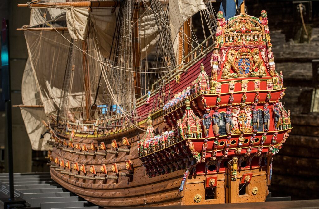 Maquete em escala detalhada do navio Vasa mostrando o casco vermelho vibrante e as esculturas barrocas douradas e coloridas da decoração original de 1628, exposta no Museu Vasa em Estocolmo