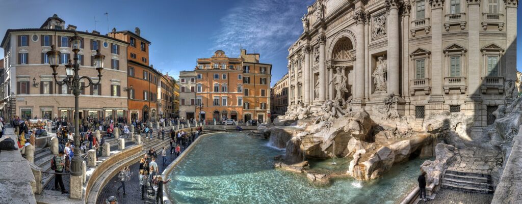 Vista panorâmica da Fontana di Trevi em Roma mostrando a fonte barroca, praça lotada de turistas, edifícios coloridos do centro histórico e águas cristalinas