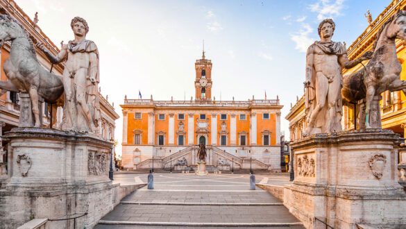 Piazza del Campidoglio em Roma mostrando estátuas dos Dioscuri (Castor e Pólux) com cavalos, Palazzo Senatorio com fachada laranja e torre do relógio, escadaria monumental e praça simétrica projetada por Michelangelo