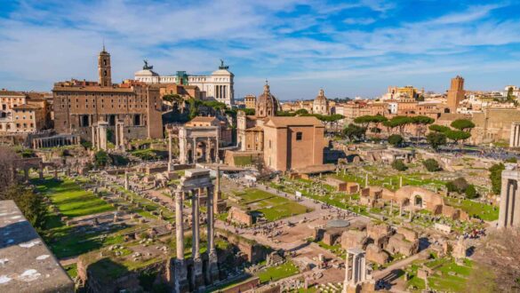 Vista panorâmica do Fórum Romano em Roma Itália mostrando ruínas antigas com colunas, templos, Arco de Septímio Severo, áreas verdes e ao fundo o monumento Vittoriano e skyline da cidade eterna sob céu azul
