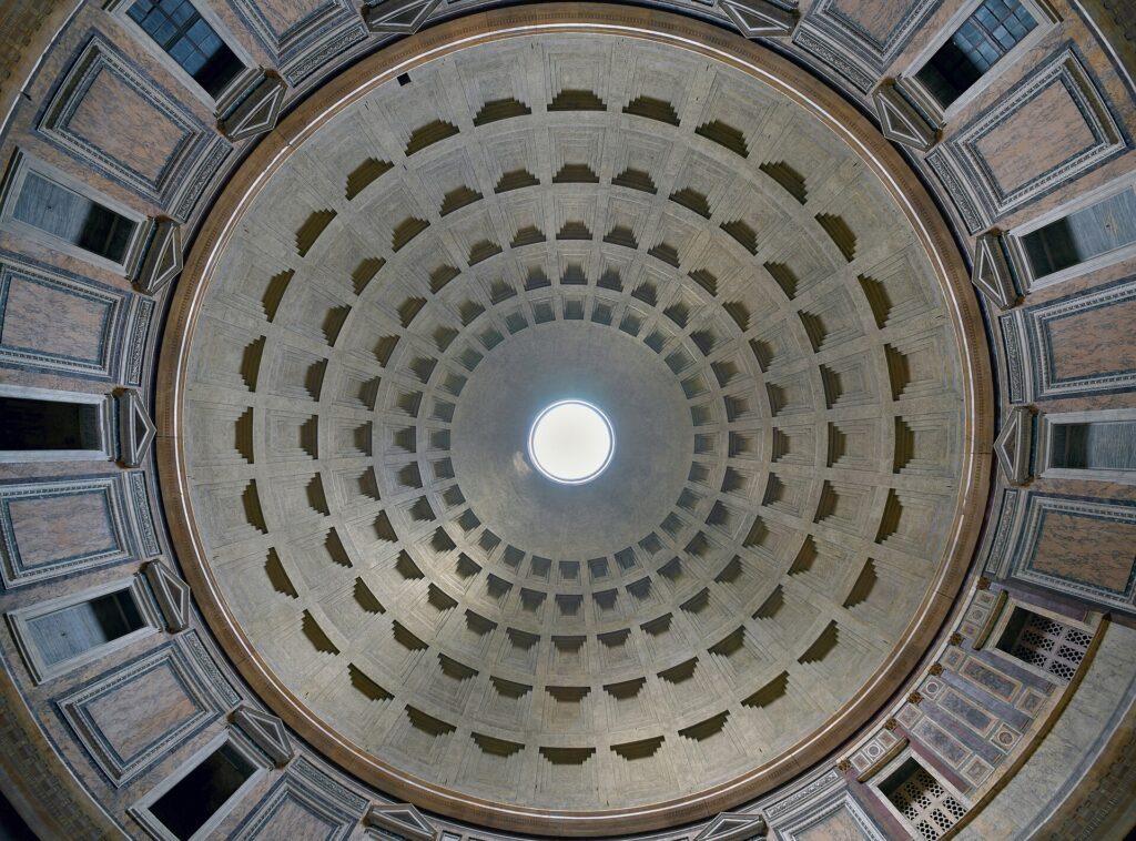 Cúpula do Panteão de Roma vista de baixo mostrando óculo central circular com luz natural, caixotões concêntricos em concreto, mármores coloridos nas paredes e janelas laterais