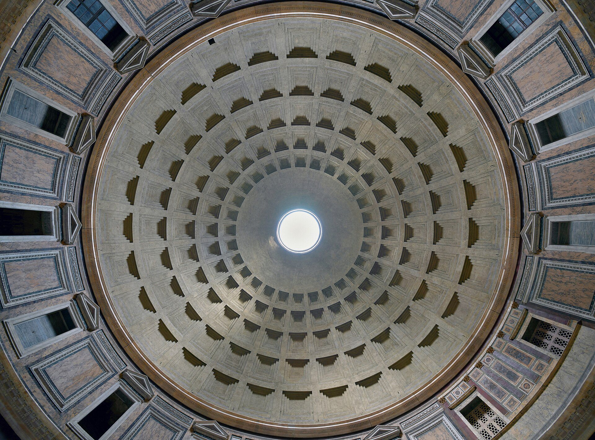 Cúpula do Panteão de Roma vista de baixo mostrando óculo central circular com luz natural, caixotões concêntricos em concreto, mármores coloridos nas paredes e janelas laterais