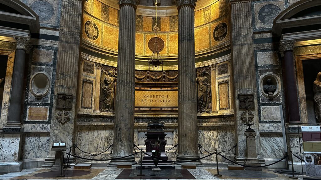 Interior do Panteão de Roma mostrando túmulo real de Umberto I Rei da Itália com colunas de mármore, painéis decorativos dourados, estátuas de bronze em nichos, inscrição VMBERTO I RE D'ITALIA e ornamentação em mármore colorido
