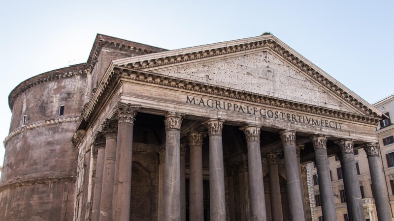 Panteão de Roma mostrando fachada com pórtico de colunas coríntias de granito, frontão triangular, inscrição latina M AGRIPPA L F COS TERTIVM FECIT e cúpula rotunda visível ao fundo