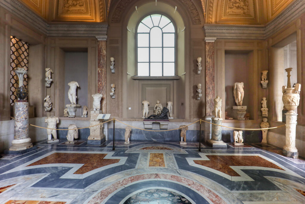 Galleria dei Candelabri nos Museus do Vaticano, corredor com estátuas clássicas, candelabros e piso de mármore geométrico