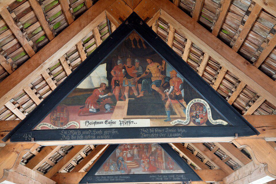 Pintura triangular de Hans Heinrich Wägmann com cena de São Maurício, brasões de doadores e inscrição em alemão antigo, nas vigas do telhado da Kapellbrücke, Lucerna, Suíça